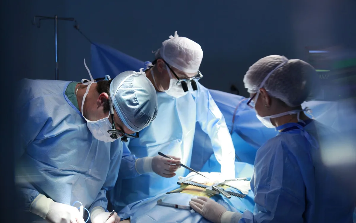 Surgeons in sterile gowns working over a draped sterile field